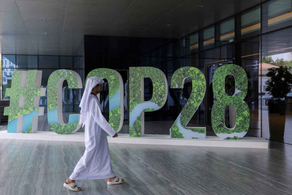 A person walks past a "#COP28" sign during The Changemaker Majlis, a one-day CEO-level thought leadership workshop focused...