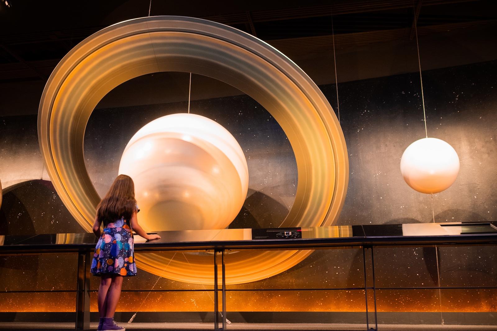 Child stands before large planet display in museum